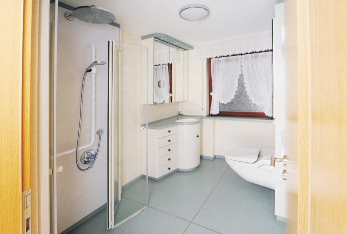 Betrachtung der Badlösung durch die Eingangstüre aus dem Wohnzimmer in modularer Bauweise und Creanit® Boden