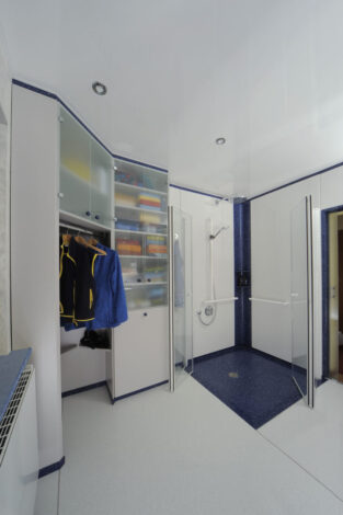 Kleider und Wäscheschrank mit nach außen geöffneten Duschtüren, ganz rechts geöffnete Schiebetüre