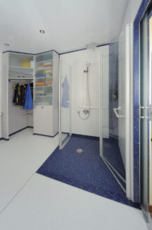 Kleider und Wäscheschrank und nach innen geöffneten Duschtüren, ganz rechts geöffnete Schiebetüre